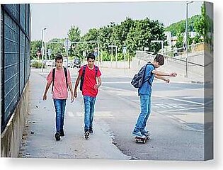 Friends Walking With Boy Skateboarding On Street Canvas Print