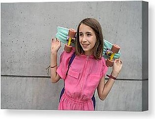 Smiling Teenage Girl Holding A Skateboard In Front Of Concret Wall Canvas Print